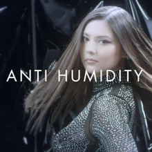 A model wearing a sparkling dark top appears with her hair flowing across the frame. The words “ANTI HUMIDITY” are overlaid across the centre.